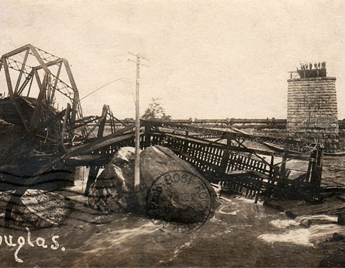 A group of men gather on the pier of the collapsed bridge.