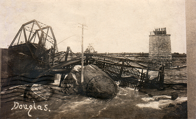 A group of men gather on the pier of the collapsed bridge.